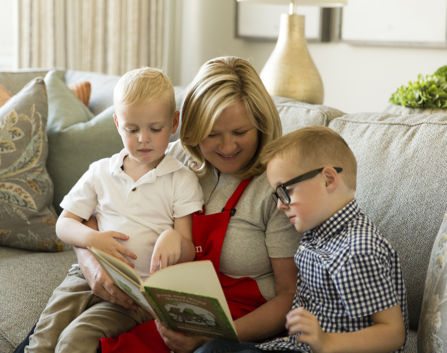 Kids Village Private School Founder Ann Whittaker and her grandsons in the library at Kids Village sitting and reading a book on the couch