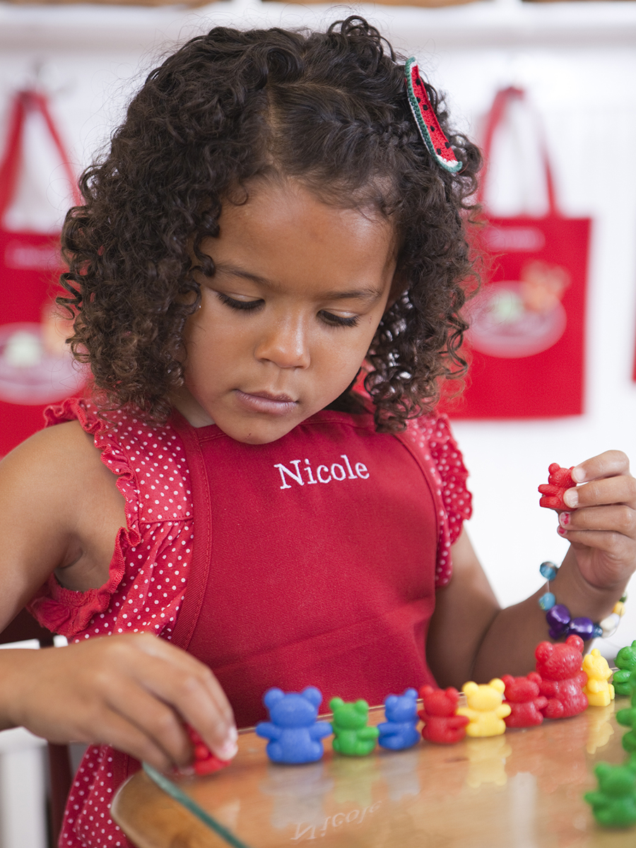 Young girl using counting bear manipulative to learn math after enrolling in Kids Village in Orem